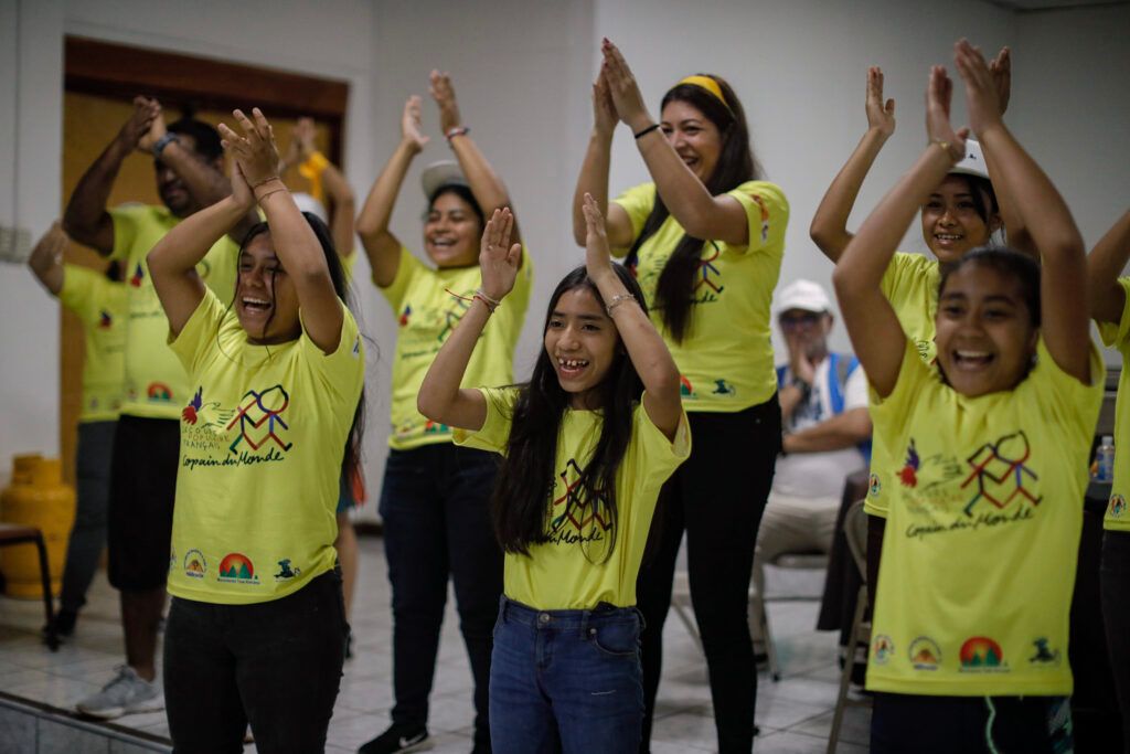 Des Copain du Monde applaudissent à mains levées.