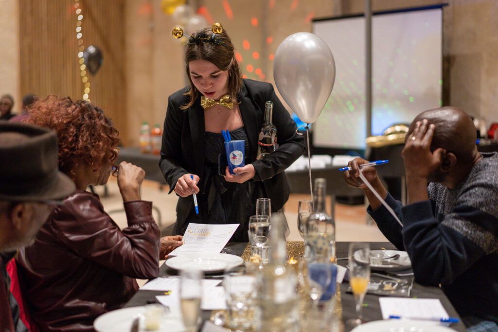 Une bénévole explique le menu aux des personnes aidées qui réveillonnent.