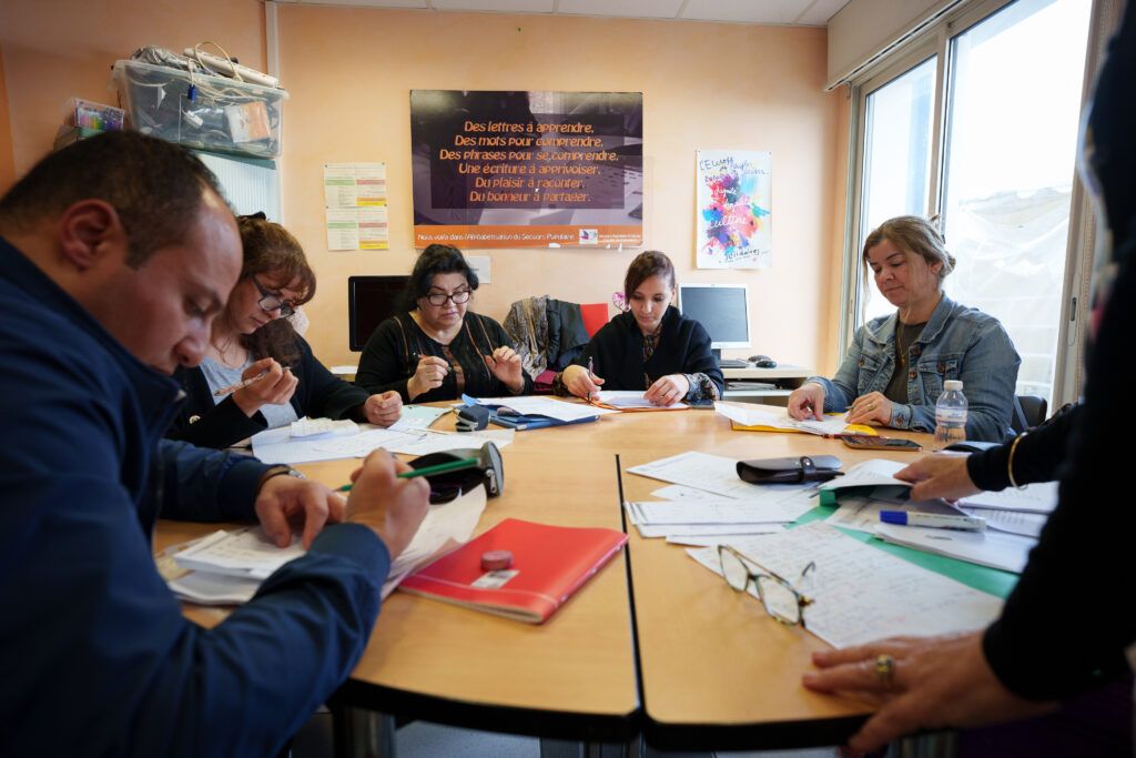 Des personnes aidées prennent des cours d'alphabétisation.