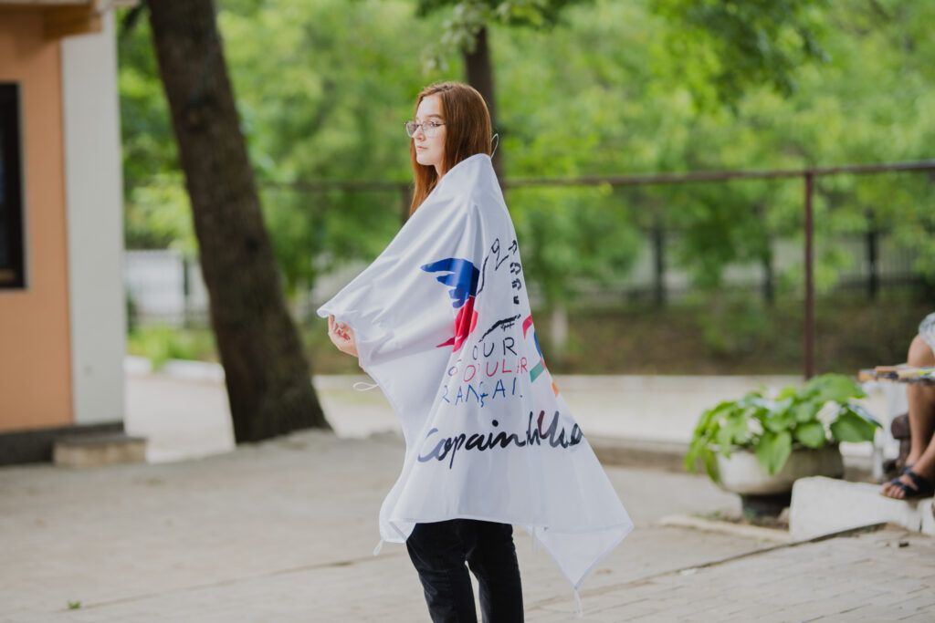 Une jeune fille s'enveloppe d'un drapeau au logo des Copain du Monde.