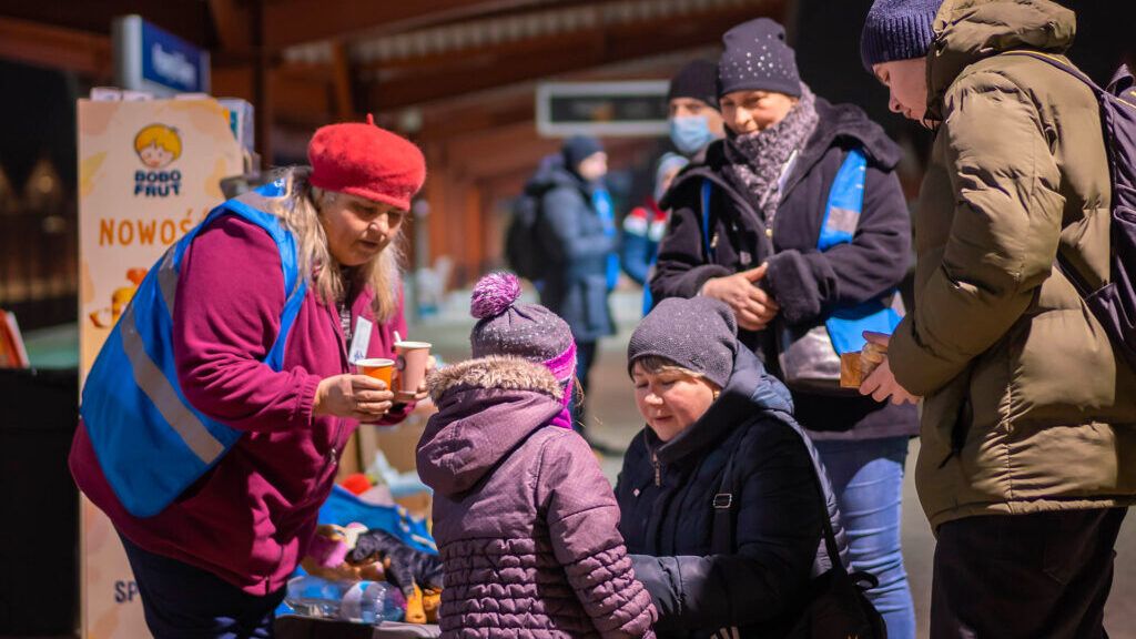 Des bénévoles offrent des boissons chaudes aux réfugiés qui arrivent.