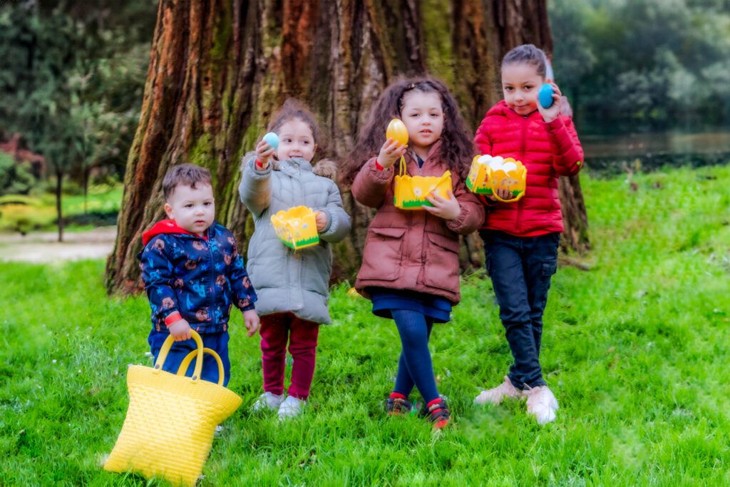 4 enfants, alignés dans une forêt, montrent les œufs qu'ils ont pu collecter lors d'une chasse aux œufs.