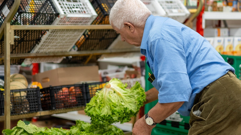 Un homme choisit une salade sur un marché
