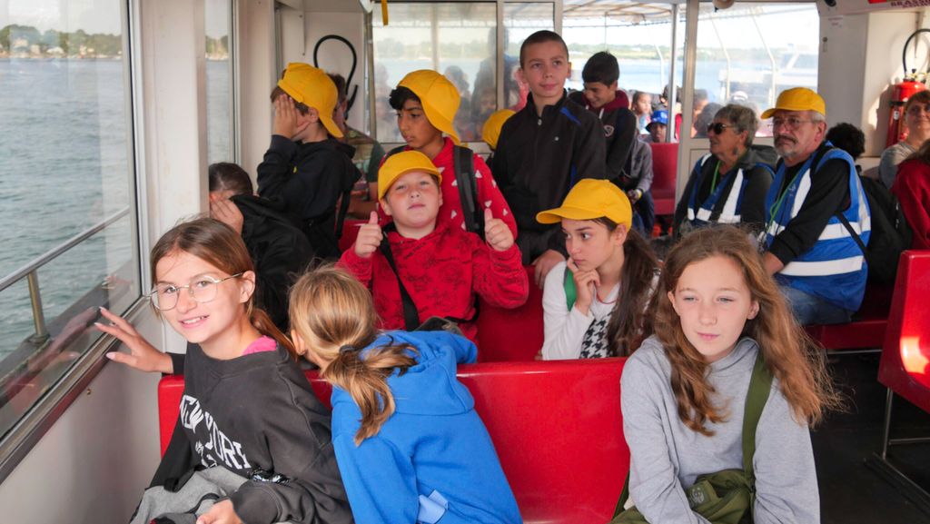 Plusieurs enfants à bord du bateau, l'un levant les pouces en l'air.