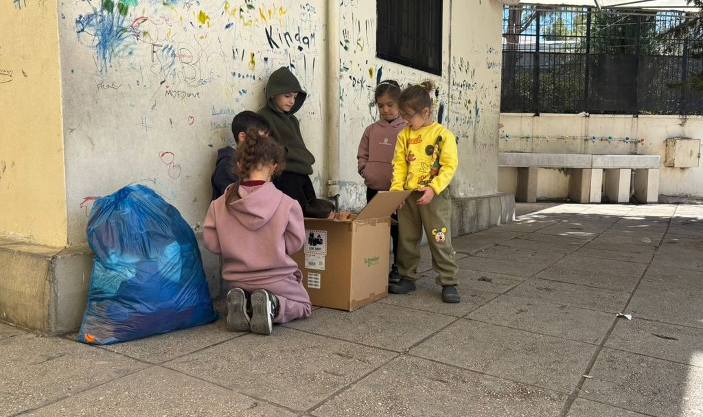 Des enfants des familles déplacées jouent avec un carton dans l'école d'Abra - 5 mars 2026, Saïda, Liban