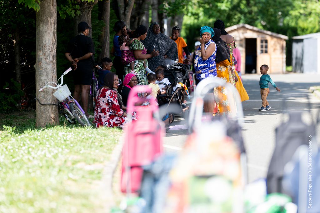 Plusieurs cadis de course et un groupe de personnes aidées derrière qui attendent l'ouverture du Solidaribus.