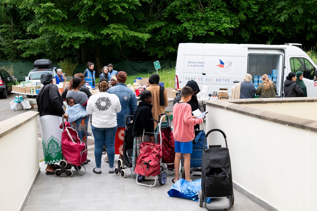 Un groupe de personnes aidées qui attendent leur tour pour la distribution alimentaire du Solidaribus.