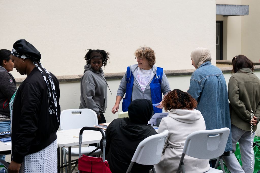 Groupe de personnes en train de discuter avec les bénévoles du Secours populaire.