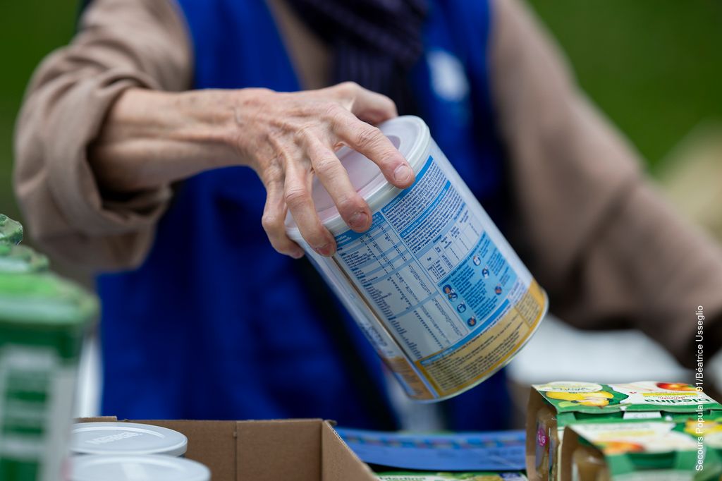 Une bénévole qui porte de la poudre pour bébé au Solidaribus.
