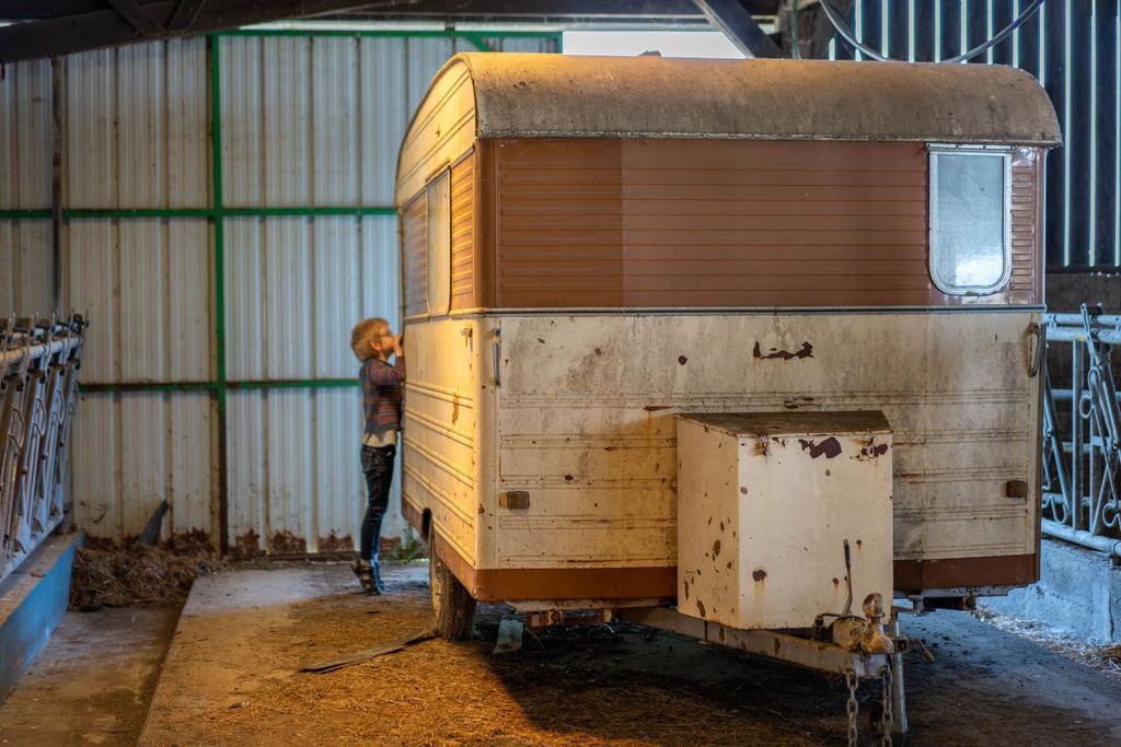 Un enfant regarde à travers la vitre d'une caravane abandonnée