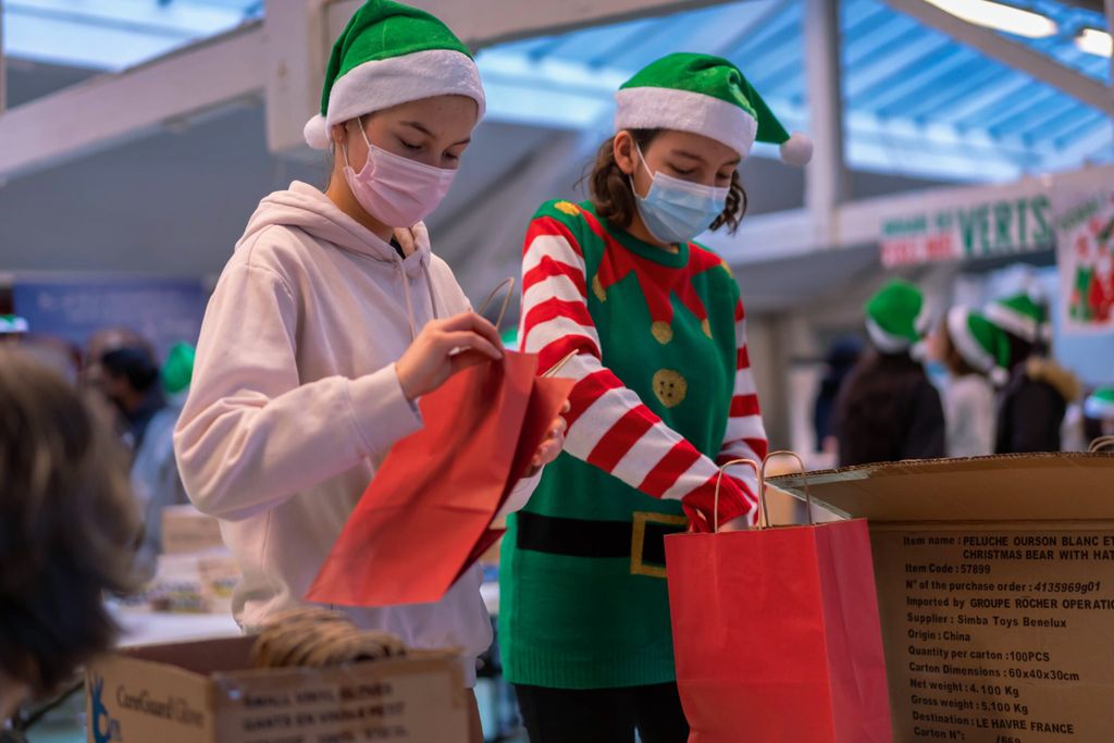 Deux jeunes bénévoles remplissent les colis de Noël.