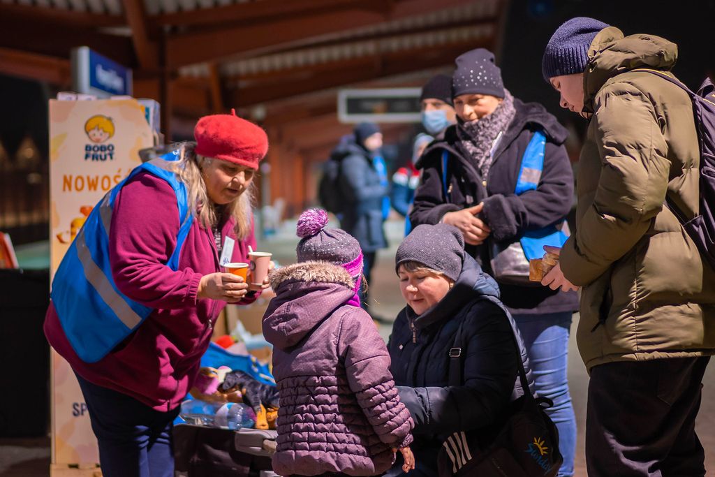 Des bénévoles offrent des boissons chaudes aux réfugiés qui arrivent.