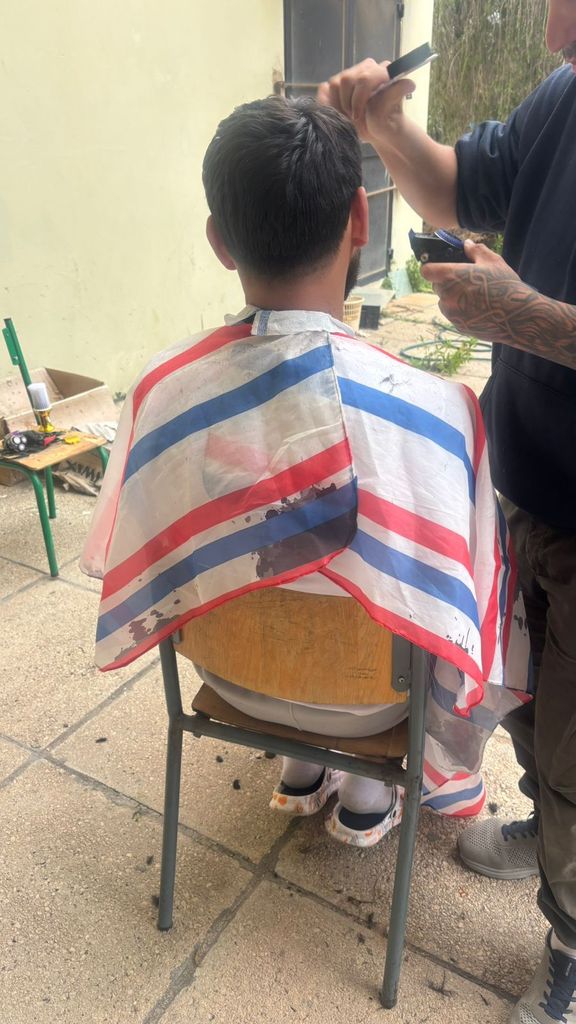 Un homme assis sur un siège d'école se fait coiffer - 5 mars 2026, Saïda, Liban