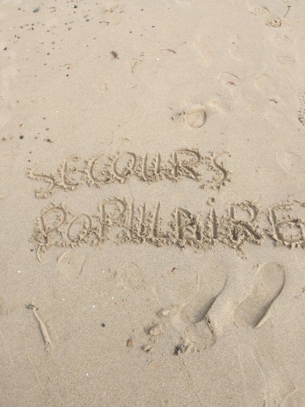 inscription "Secours populaire" dans le sable
