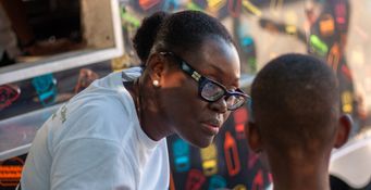 Martine Canal, présidente de l’AHCD, partenaire du Secours populaire en Haïti, avec un enfant déplacé accompagné dans le cadre d’un programme de soutien psychologique. Parc d’attraction de Lakay, Port-au-Prince, Noël 2025.