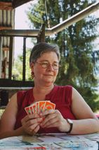 Une personne aidée jouant à un jeu de carte, assise à une table.