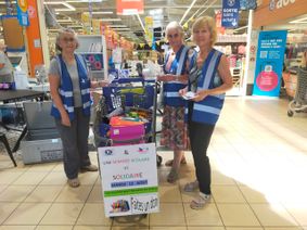 Des bénévoles du Secours Populaire de Millau avec des caddies, collectant des fournitures scolaires à l'entrée su supermarché Leclerc de Creissels.