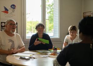 Des bénévoles d'un comité du Secours populaire, souriants, sont réunis autour d'une table.