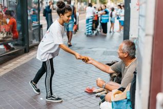 Isra, Copain du Monde à Marseille, remet à une personne sans-abri de quoi se restaurer.