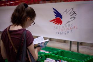 Une femme, de dos, regarde un livre lors d'une foire aux livres proposée par le Secours populaire français.