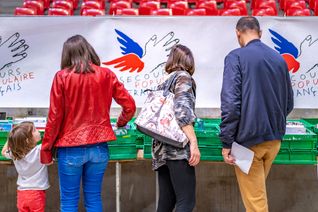 Plusieurs personnes, de dos, regardent les produits proposés lors d'une braderie organisée par le Secours populaire français.