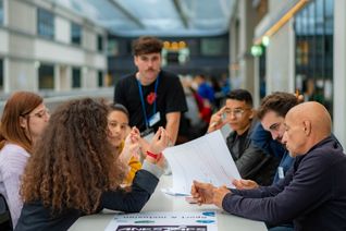 Des jeunes bénévoles , assis autour d'une table discutent lors d'un atelier.