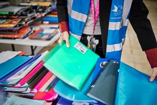 Un bénévole rassemble des fournitures scolaires lors d'une opération menée par le Secours populaire.