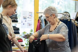 Interactions entre une bénévole du Secours populaire français et une jeune femme, venue voir des vêtements lors d'une braderie.