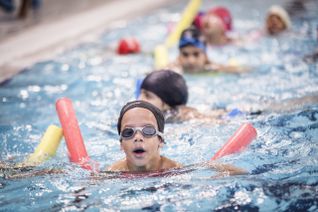 Enfant aidé par le Secours populaire qui nage dans une piscine.