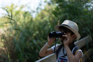 Un enfant regarde au loin avec des jumelles