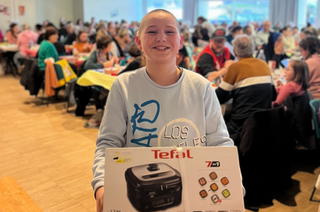 Une jeune fille présentant son lot gagnant au loto solidaire du Secours populaire du Calvados