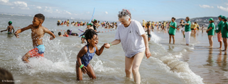 une enfant et une adulte sont les pieds dans l'eau et se tiennent par la main