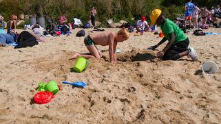 Deux enfants creusent un trou dans le sable.