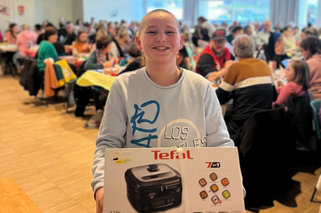 Une jeune fille présentant son lot gagnant au loto solidaire du Secours populaire du Calvados