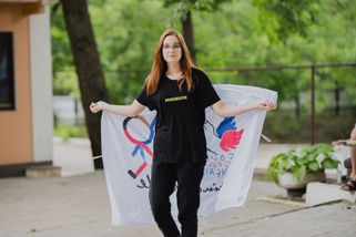 Une jeune fille brandit derrière son dos, d'un drapeau au logo des Copain du Monde.
