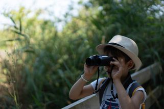 Un enfant regarde au loin avec des jumelles