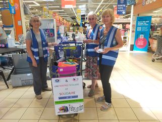 Des bénévoles du Secours Populaire de Millau avec des caddies, collectant des fournitures scolaires à l'entrée su supermarché Leclerc de Creissels.