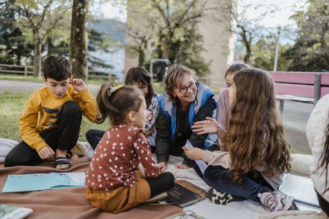 Valérie, bénévole du Secours populaire de Privas, lit des histoires aux enfants au pied d’un immeuble, dans un quartier populaire de Privas, en Ardèche, le mercredi 2 octobre 2024.