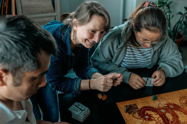 Nelly, animatrice de l’atelier « jeux de société » du Secours populaire de Guéret, entournée de Sam et Sangmo, deux apprenants en français.