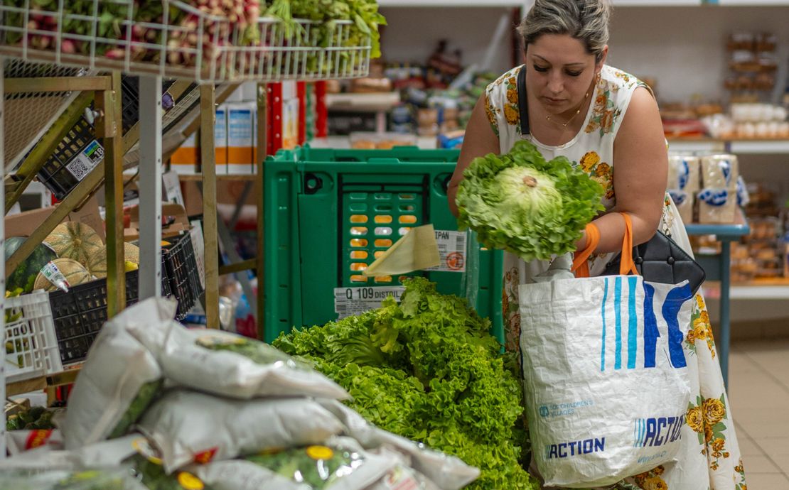 Une femme bénéficiaire de l'aide alimentaire choisit une salade à mettre dans son sac de courses.
