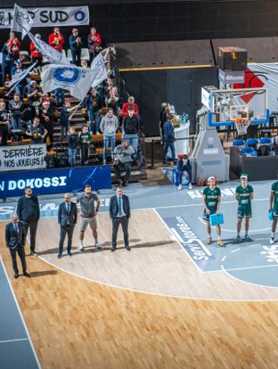 Une trentaine d’étudiants dijonnais, accompagnés par le Secours populaire, sont invités à assister au match de championnat de France de basket Dijon/ limoges le 16 décembre 2023 Les joueurs, qui portent un bonnet PNV, organisent une collecte de cadeau sur le terrain.