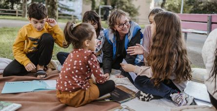 Valérie, bénévole du Secours populaire de Privas, lit des histoires aux enfants au pied d’un immeuble, dans un quartier populaire de Privas, en Ardèche, le mercredi 2 octobre 2024.