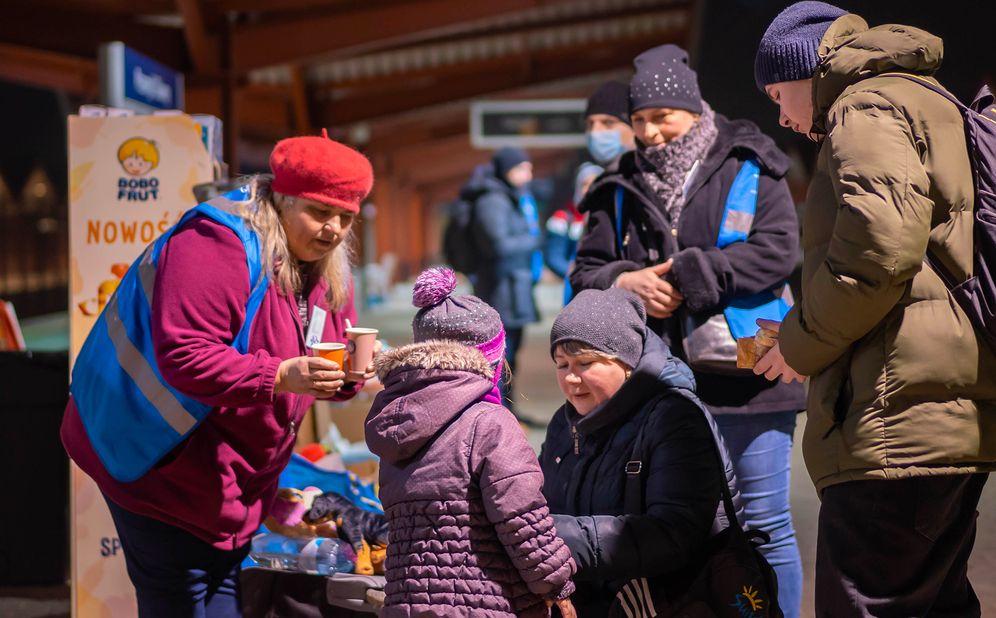 Des bénévoles offrent des boissons chaudes aux réfugiés qui arrivent.